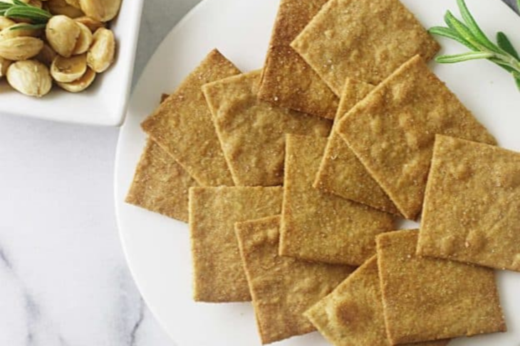 Einkorn wheat thins stacked on a plate with rosemary and marcona almonds