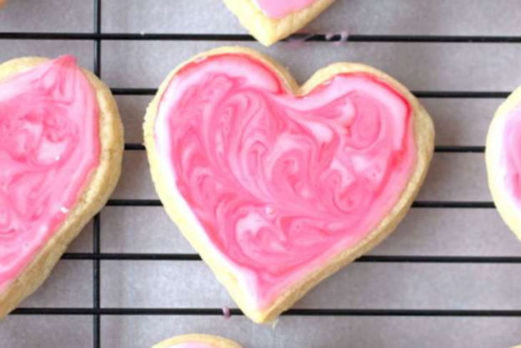 Einkorn sugar cookies shaped as hearts with swirled pink icing on a cooling rack