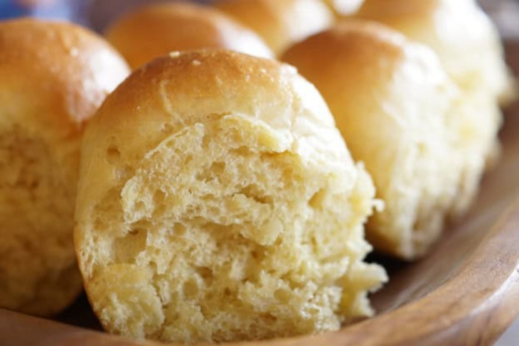 Einkorn dinner rolls in a wooden bowl, one torn open to show soft crumb